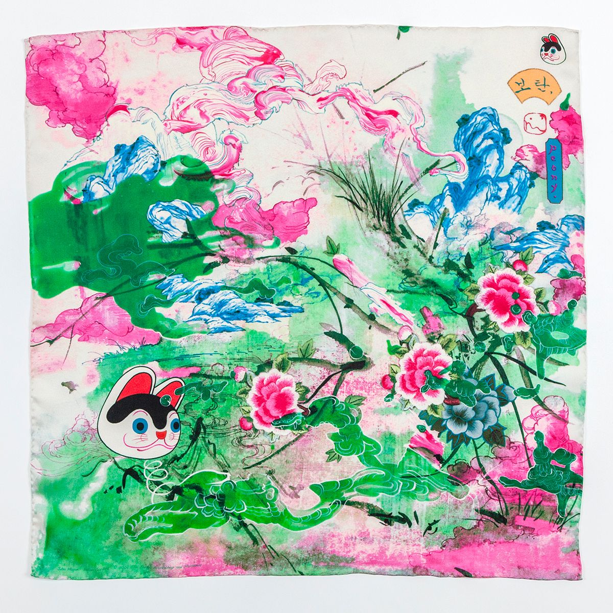 A square scarf with fluid ink drawings of pink, green, and blue clouds, intersect with drawings of mountains and peonies in an East Asian style. A drawing of a cartoon cat head floats on the left.