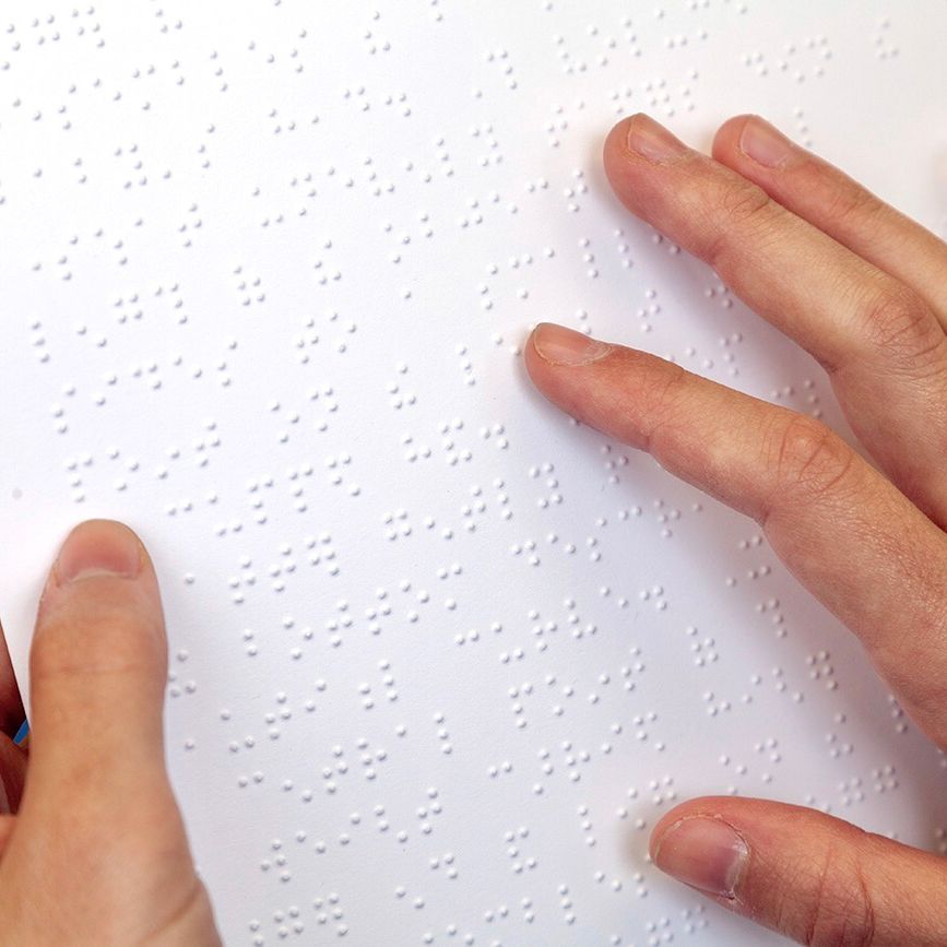 An image of a person running their fingers over the braille on the surface of the artwork.