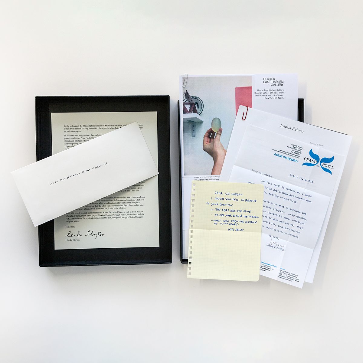 A black box sits open facing up against a white background. To the left, inside of the box, is a single letter with an envelope set on top of it. To the right, a stack of shuffled letters lies on top of the other side of the box, facing upwards.