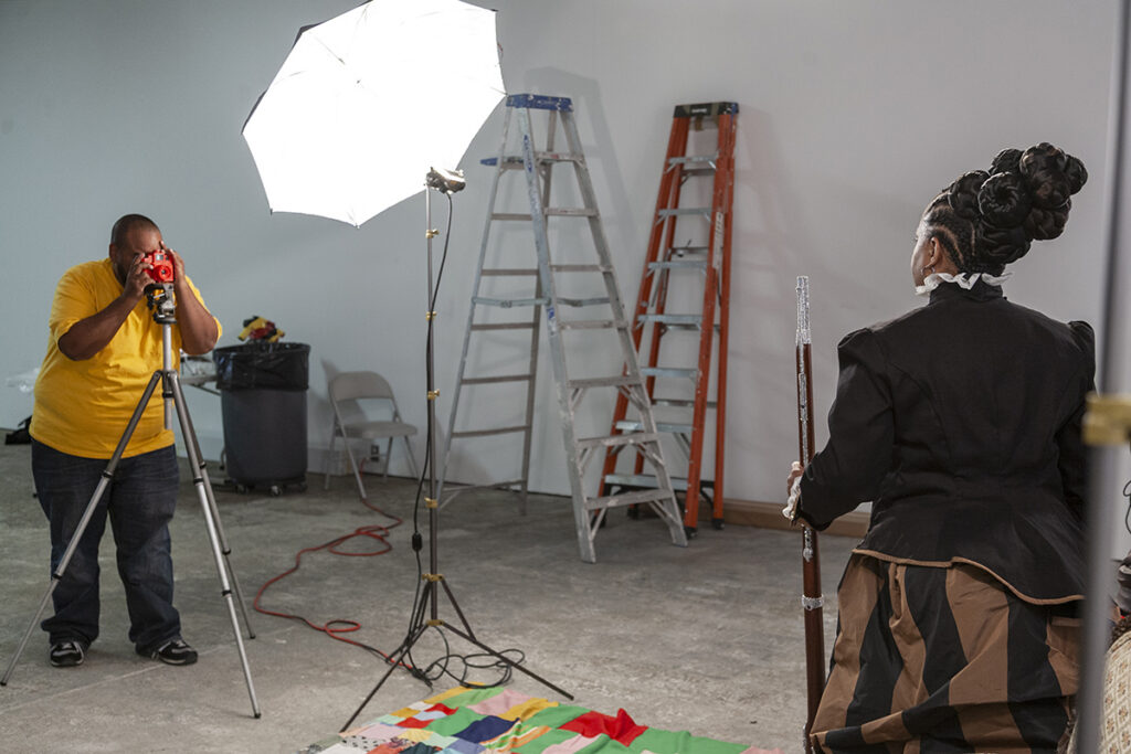 A photo studio with a photographer on the left and a woman modeling for a portrait on the right.