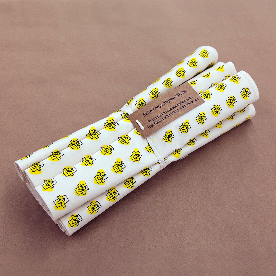 A set of white cloth napkins that have been screenprinted with a black line drawing that resembles abstract dominoes laid out in a grid. Each 