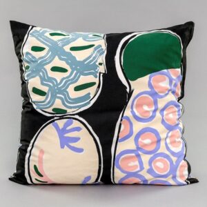 An image of a square pillow against a grey background. The pillow is a screenprinted design by Betty Woodman. The background of the design is black, with colorful pastel, loosely drawn, soft abstract shapes mimicking ceramic platters.