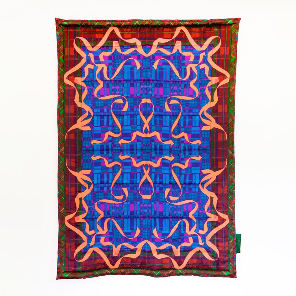 A rectangular blanket with a dark red border and deep blue center. A mirrored pattern of bright red ribbons make up the top layer of detail.