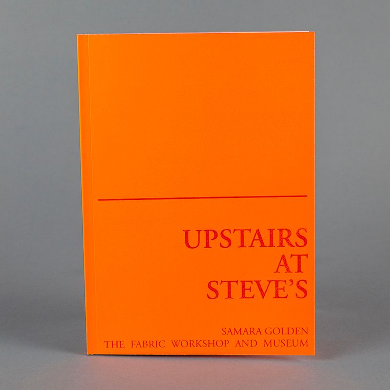 A photograph of a bright orange book standing upright. A red line divides the book cover into two; the lower half reads, 