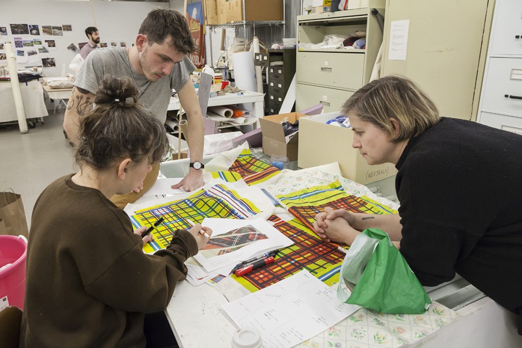 Three people (Samara Golden, Zack Ingram, Abby Lutz) reviewing materials samples in the FWM studios.