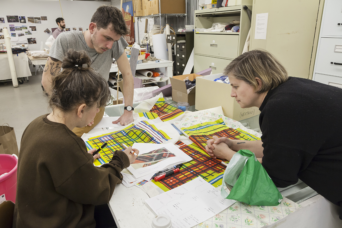 Three people (Samara Golden, Zack Ingram, Abby Lutz) reviewing materials samples in the FWM studios.