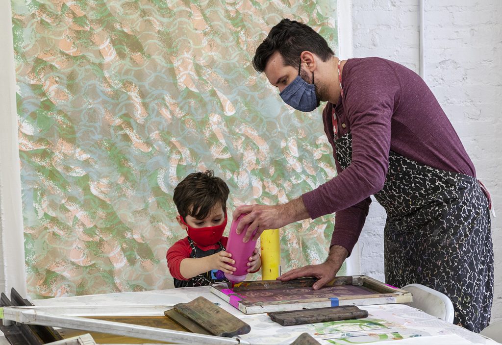 A parent and young son learn screenprinting