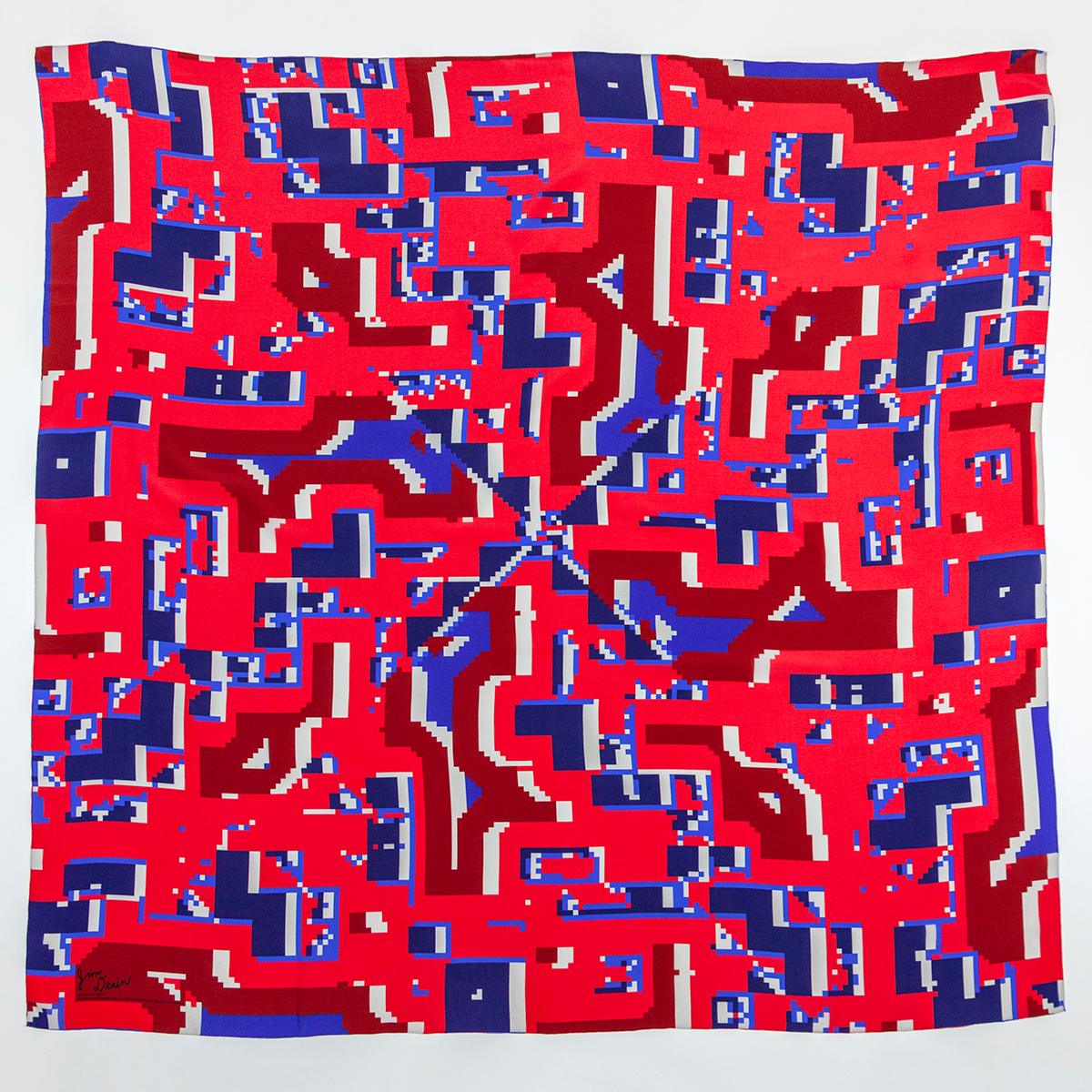 A scarf made up of geometric patterns of highly saturated reds and blues with slight shapes of white peaking through.