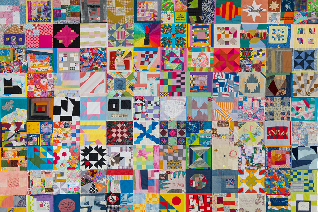 A multi-colored, multi-patterned quilt consisting of a grid that is 12 blocks wide and nearly 9 blocks tall.