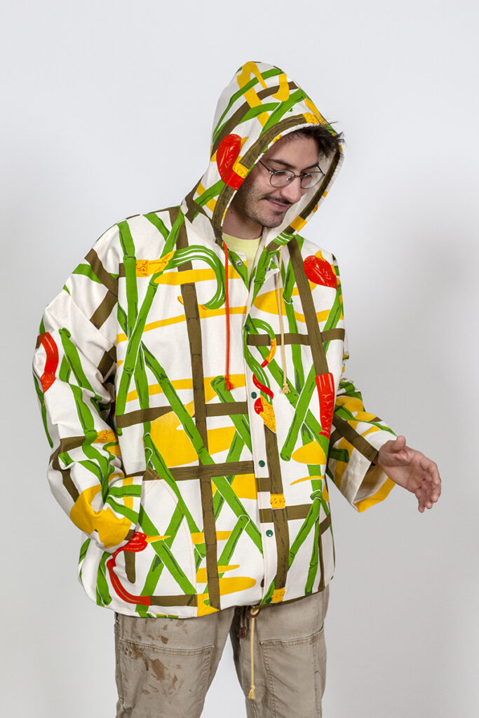 A photo of a man wearing a jacket with a screenprinted pattern of birds and bamboo.