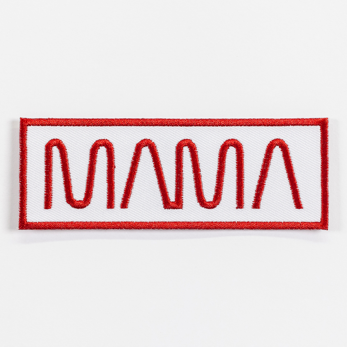 A long rectangular patch outlined in a thick red border. The embroidered text in the middle reads MAMA in a style reminiscent of the NASA logo.