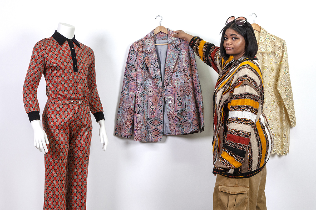 A photo of a Black woman curating a selection of vibrantly patterned garments.