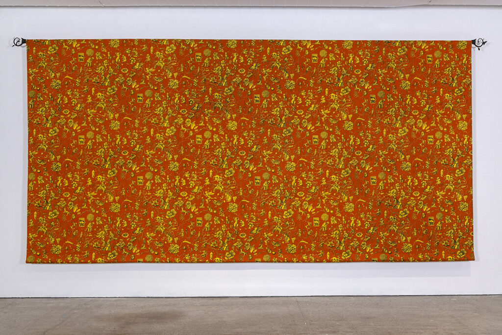A large orange tapestry hangs on a wall of a gallery. Longer than it is tall, it features numerous tiny details in yellow that suggest a repeated pattern.