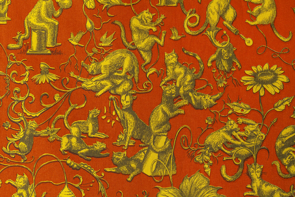 A detailed illustrated pattern of various cats engaged in strange activities. The pattern is composed of three basic colors with a red/orange ground, yellow characters, and dark gray details.