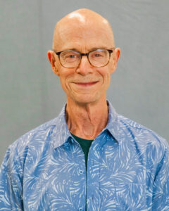 A portrait of John Killacky, an older, bald white man with glasses and a blue collared shirt.