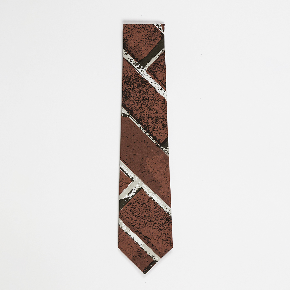 The bottom half of a folded necktie featuring a red brick pattern printed at a diagonal