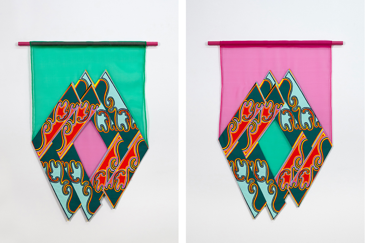 Two colorful textile wall hangings with overlapping diamond-shaped panels in a mirrored repeat pattern. The artwork on the left is framed by green fabric with a pink diamond fabric at the center. The artwork on the right is framed by pink fabric with green diamond shaped fabric at the center.