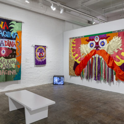 An installation view of colorful tapestries in a gallery