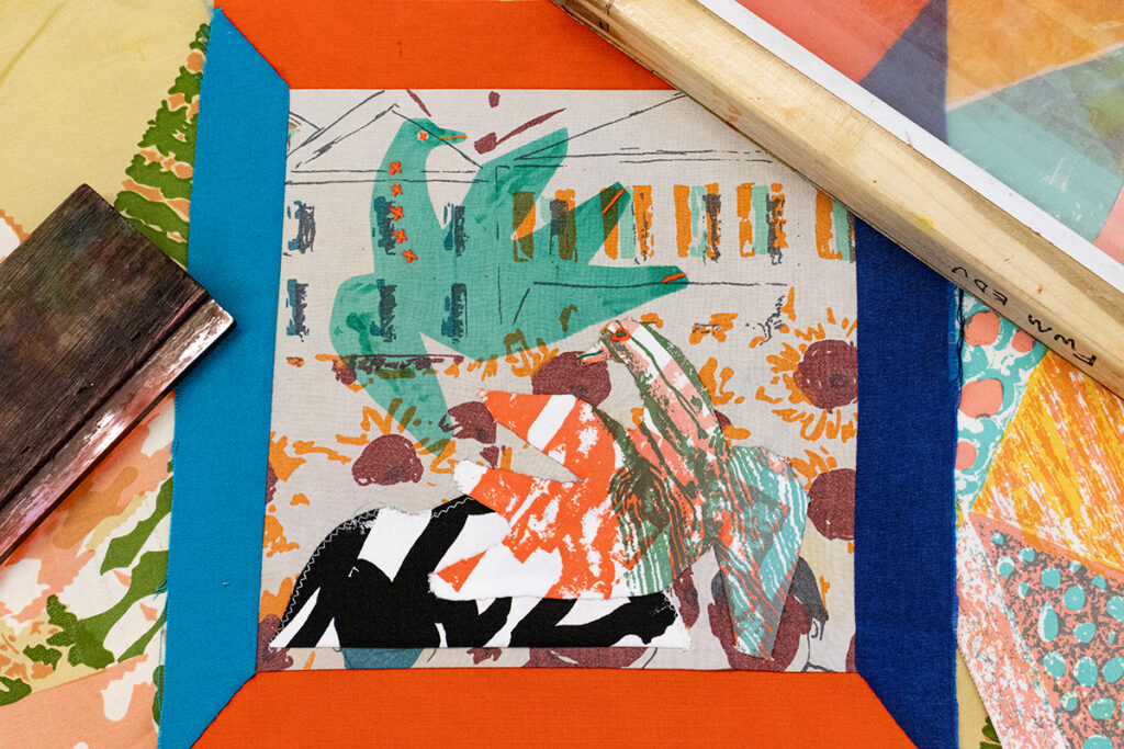 An image of a quilt square featuring a screenprinted bird and an appliqué of the reverse of the same bird motif. The square is surrounded by screenprinting materials.
