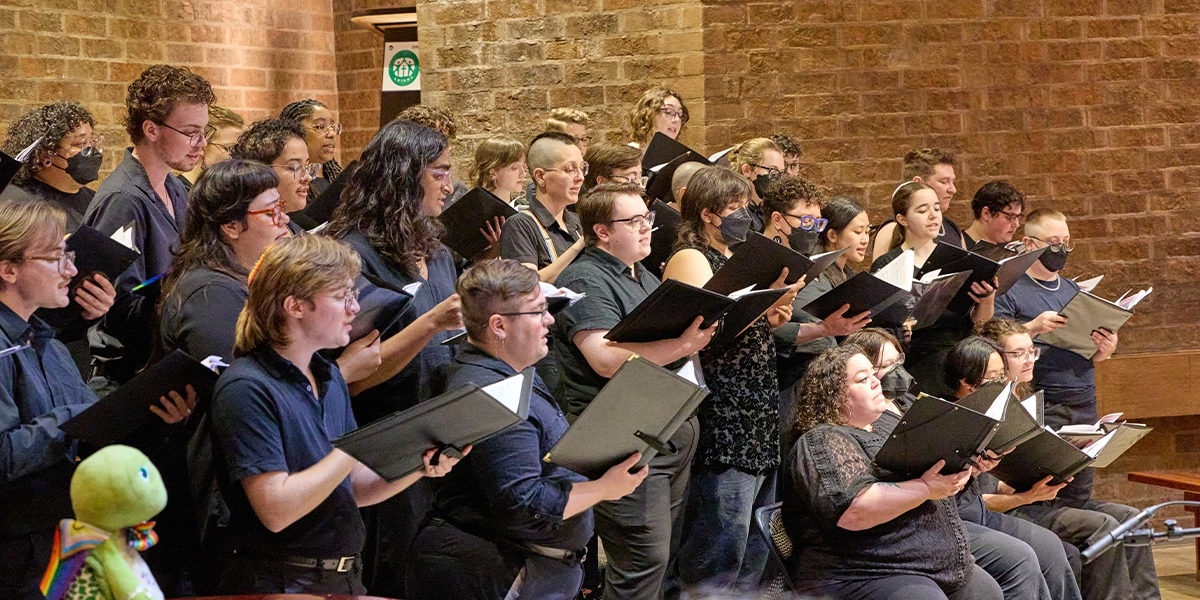 A photo of a choir performing with song books in hand.