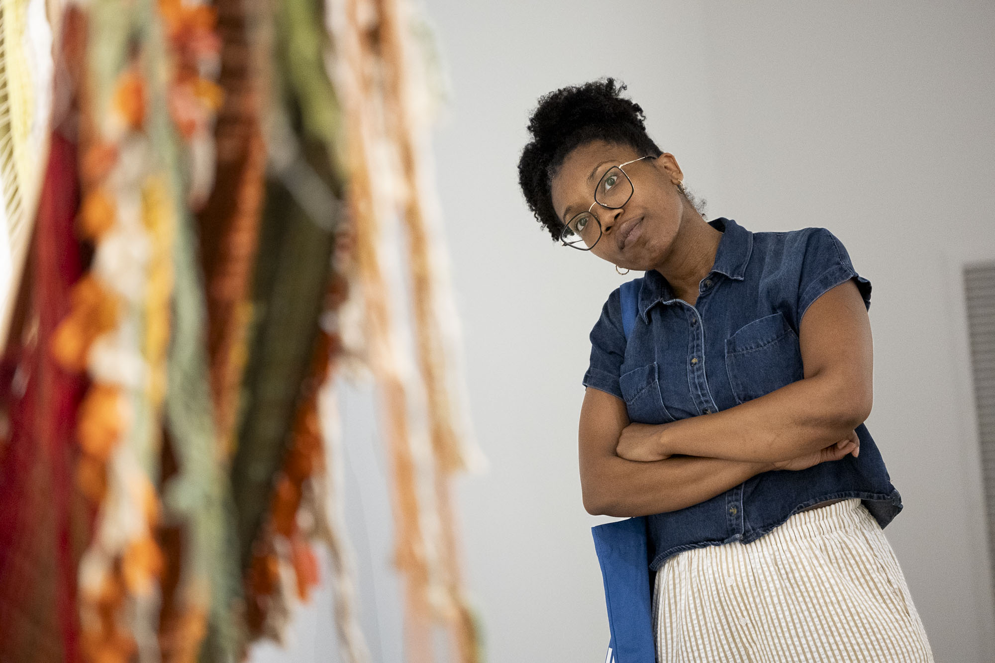 A woman tilts her head to get a better look at a large sculptural weaving in a gallery